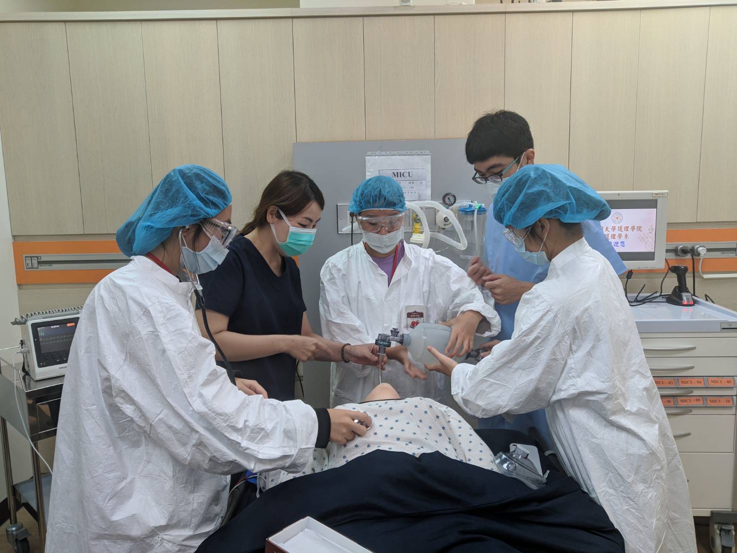 图说：亚大护理学系彭逸稘老师(左二)指导学员体验高拟真智慧病人插管。