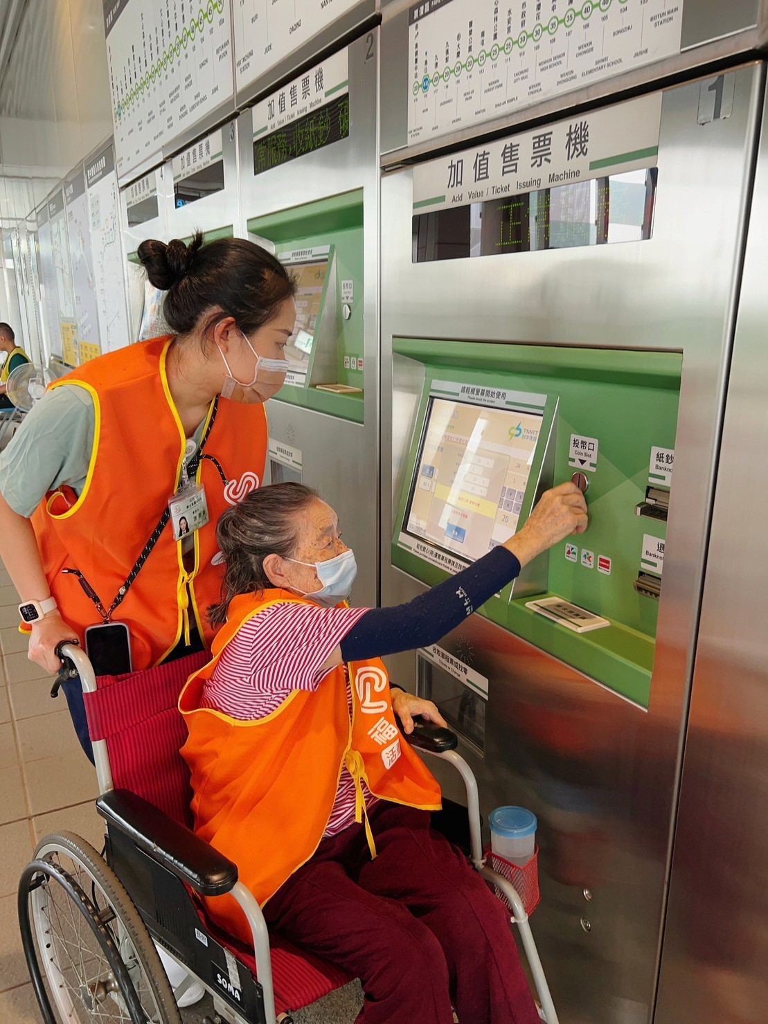 图为长辈体验使用投币式机器，购票台中捷运车票。