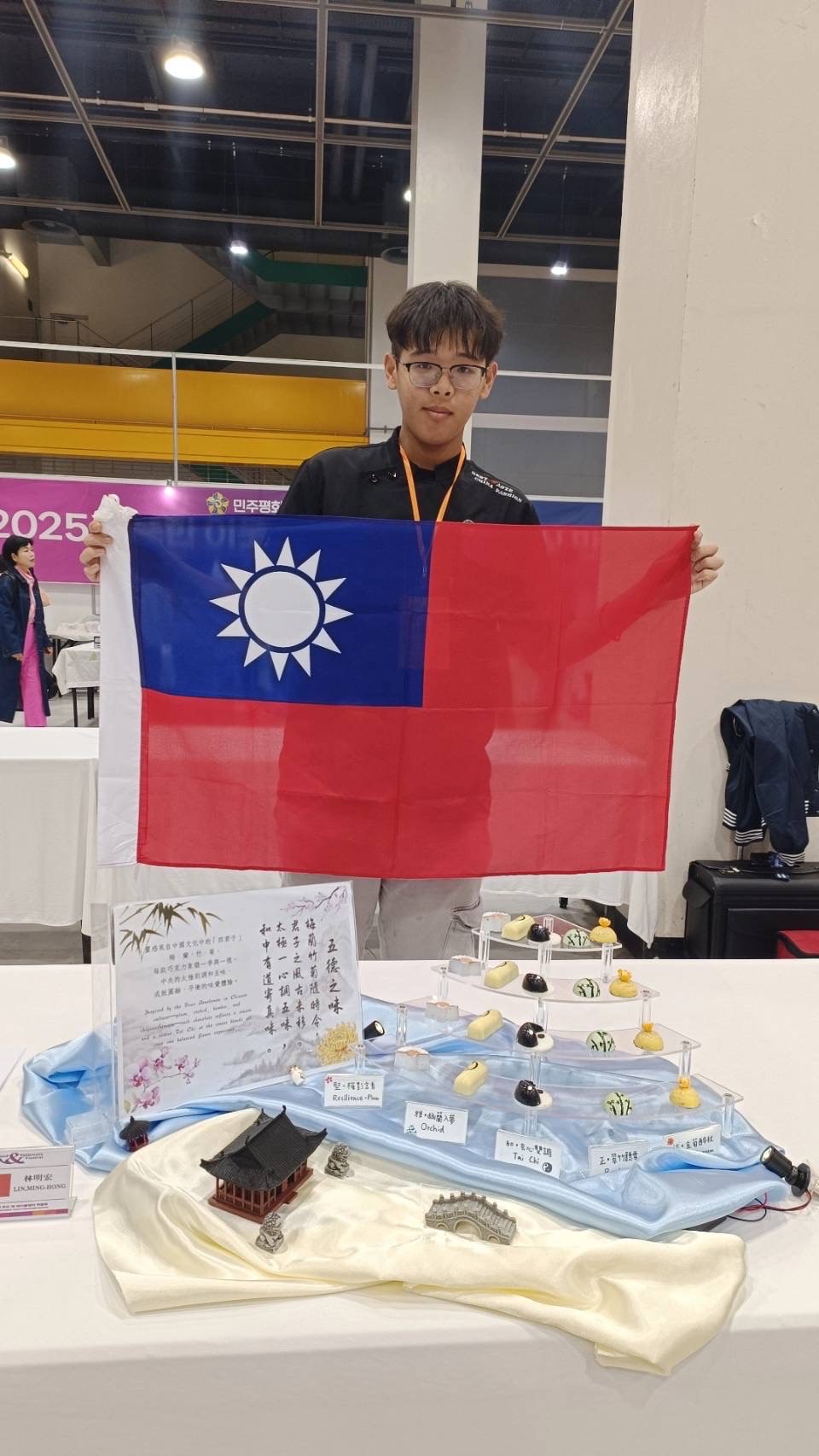 圖說：亞大護理學系林明宏同學拿國旗與得獎作品(五德之味)拍照。