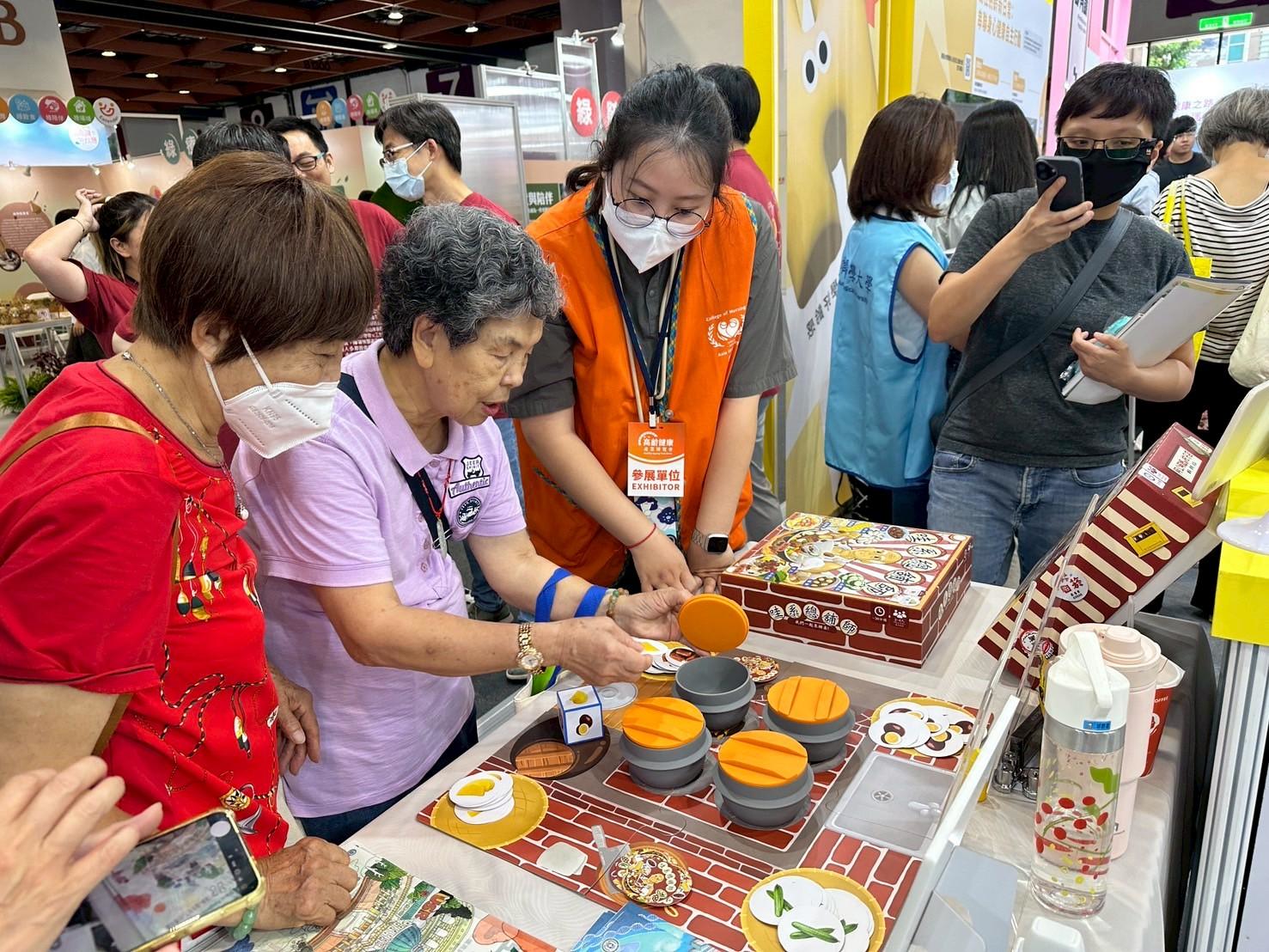 图说：护理学院与恐龙山丘文化创意有限公司合作，将USR成果商品化为《哇系总舖师》、《阿公嬷ㄟ柑仔店》等健智桌游，吸引许多民众体验、问询。
